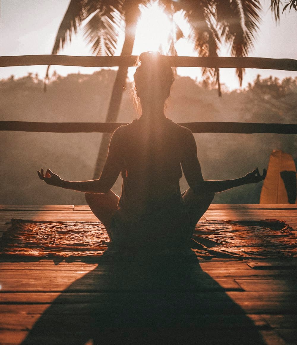 Person sitting in quiet meditation as the sun sets, evoking calm talk therapy