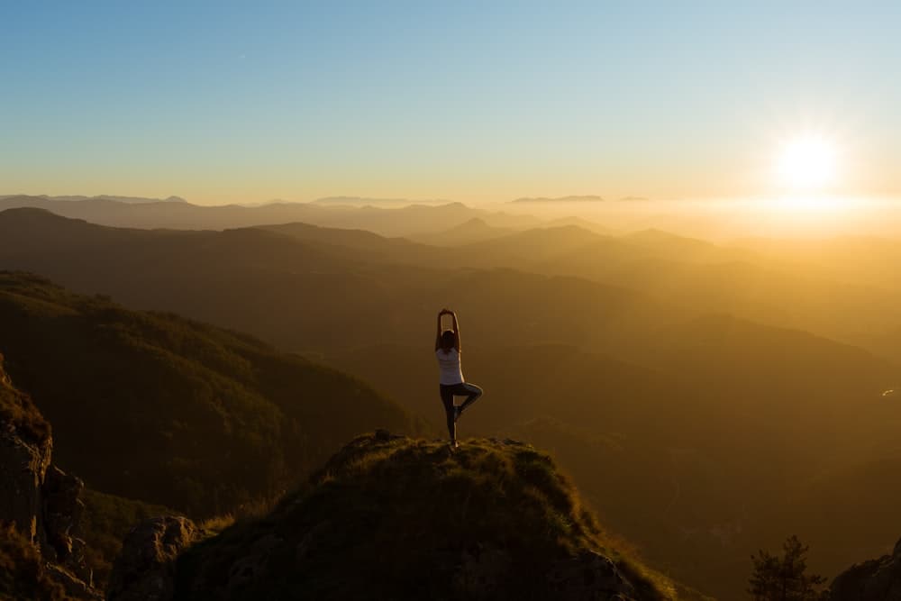 Person practicing yoga on a mountain overlook, symbolizing personal growth